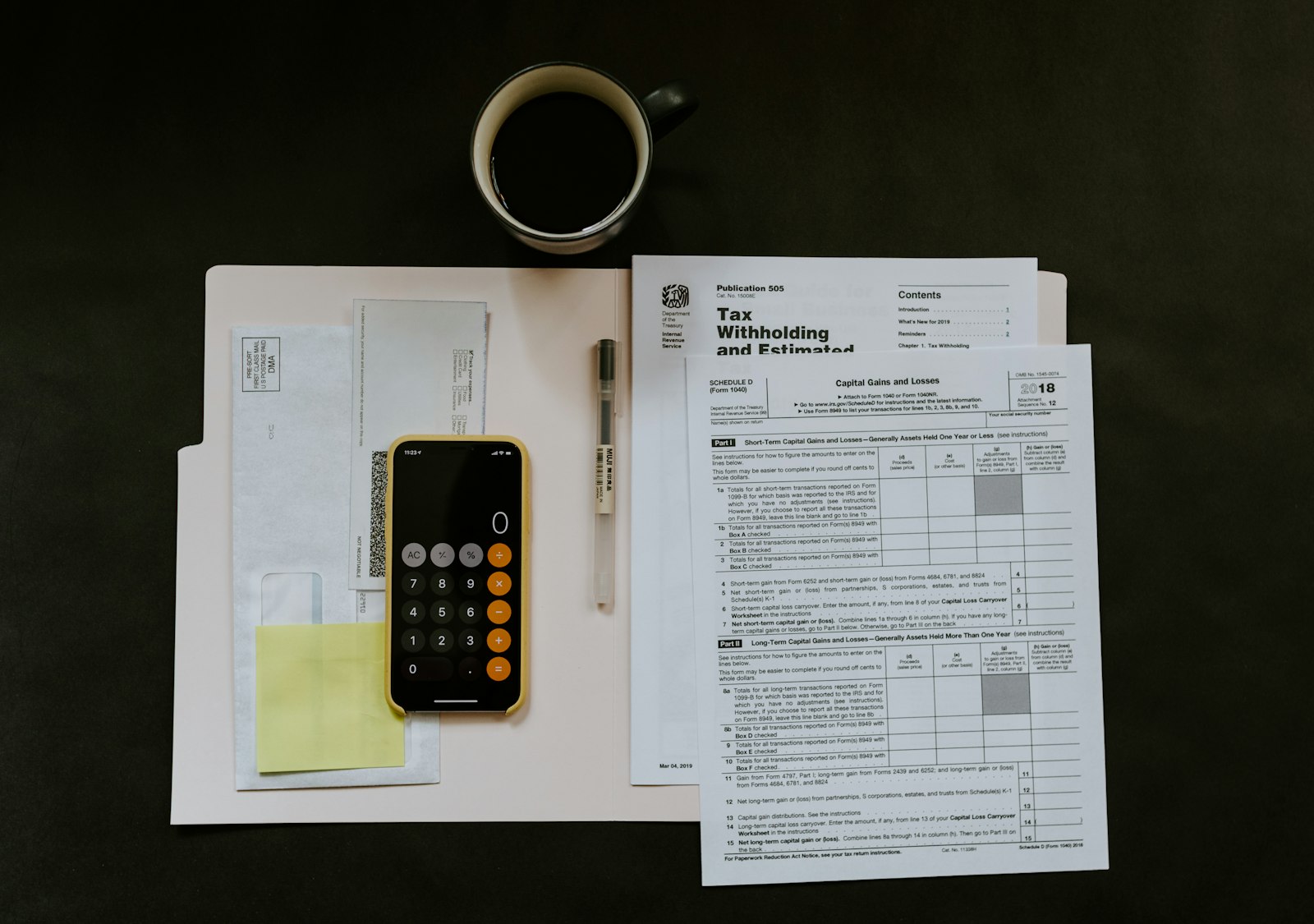 Ledger, laptop and calculator on a warm oak desk with reading light.