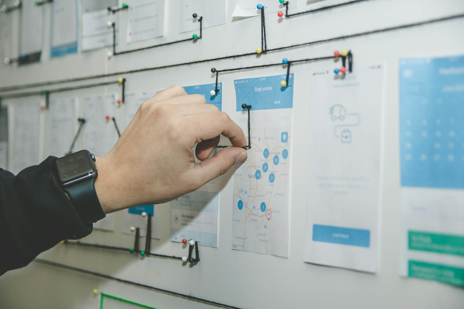 PM at a wall of sticky-notes mapping a release plan.
